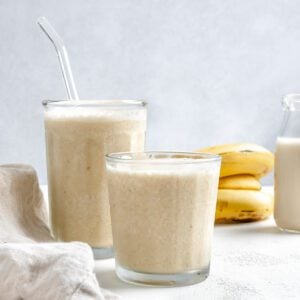 completed Banana Milkshake in two glass cups against a white background