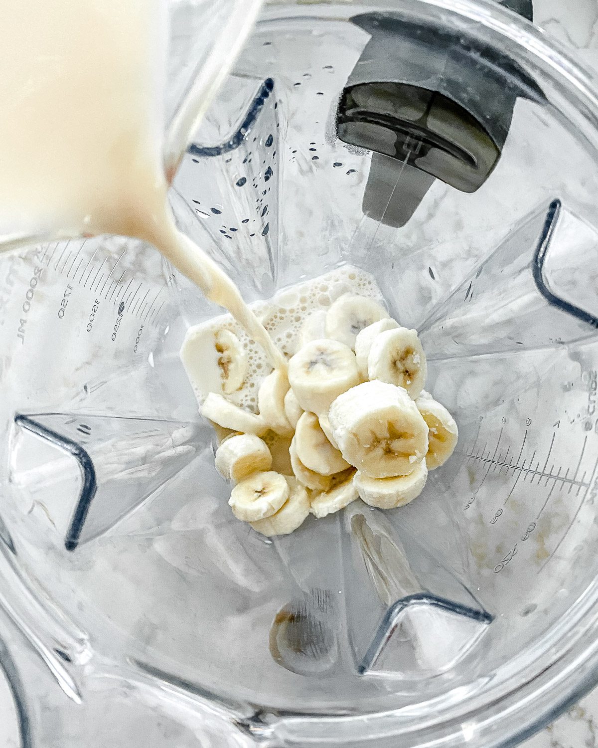 process of adding plant milk to blender for banana milkshake