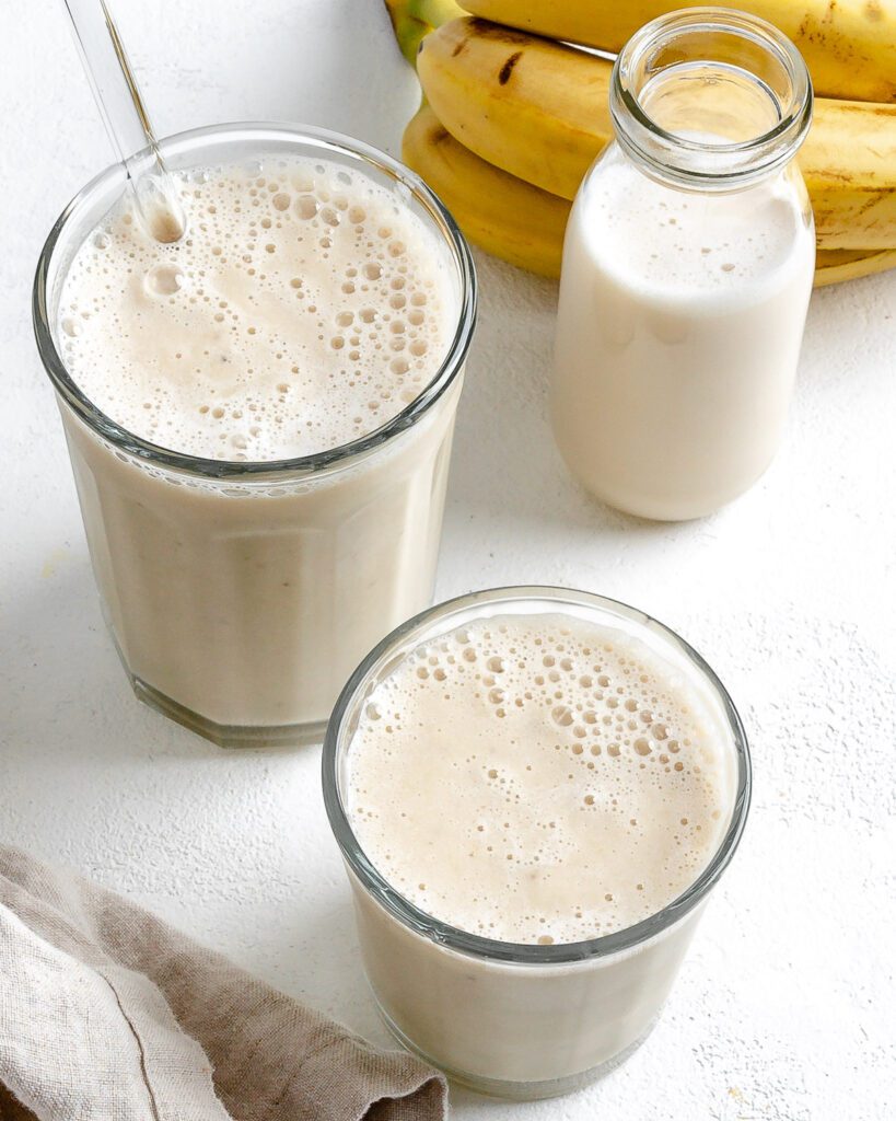 completed Banana Milkshake in two glass cups against a white background