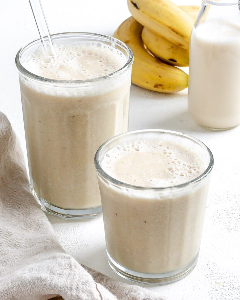 completed Banana Milkshake in two glass cups against a white background