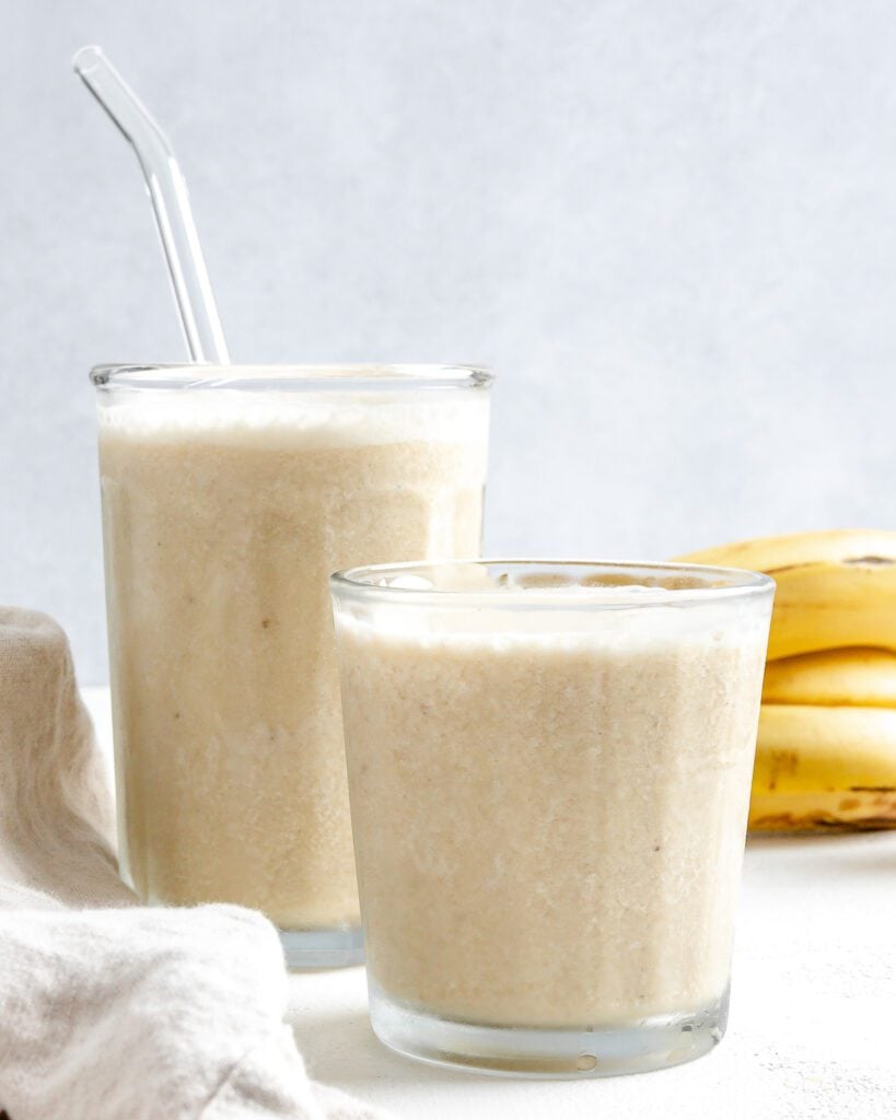 completed Banana Milkshake in two glass cups against a white background