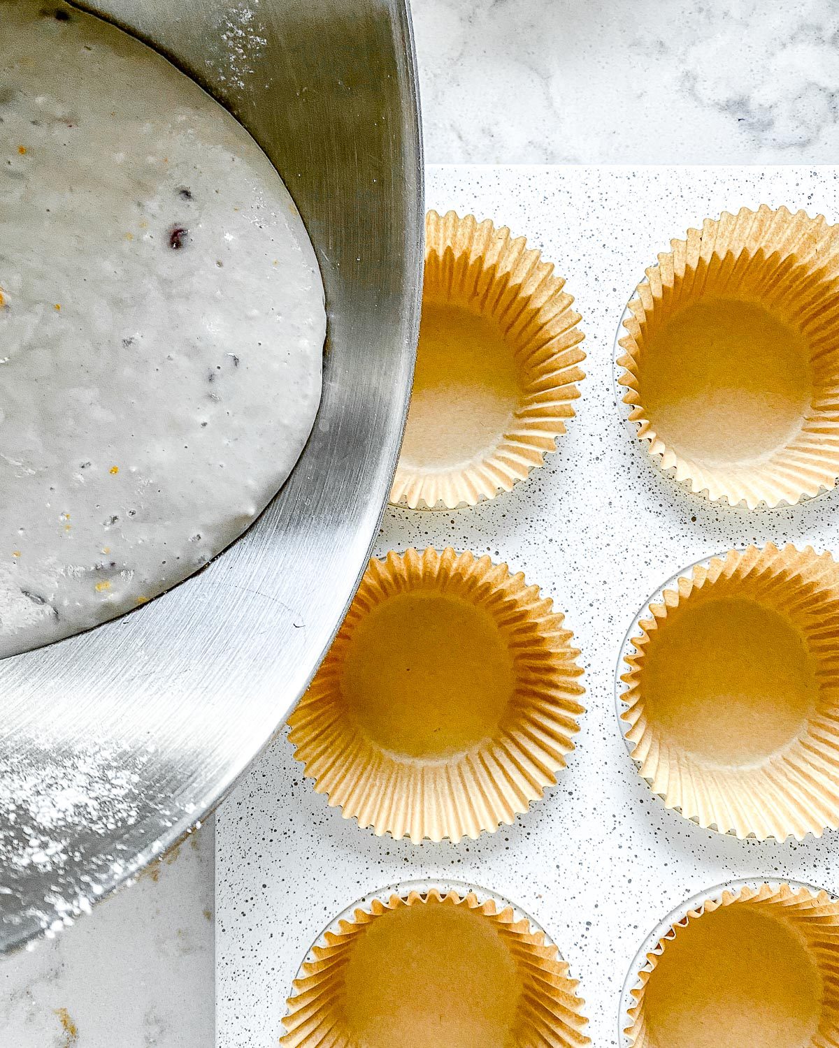 process showing the pouring of blackberry orange cupcake batter into muffin tin