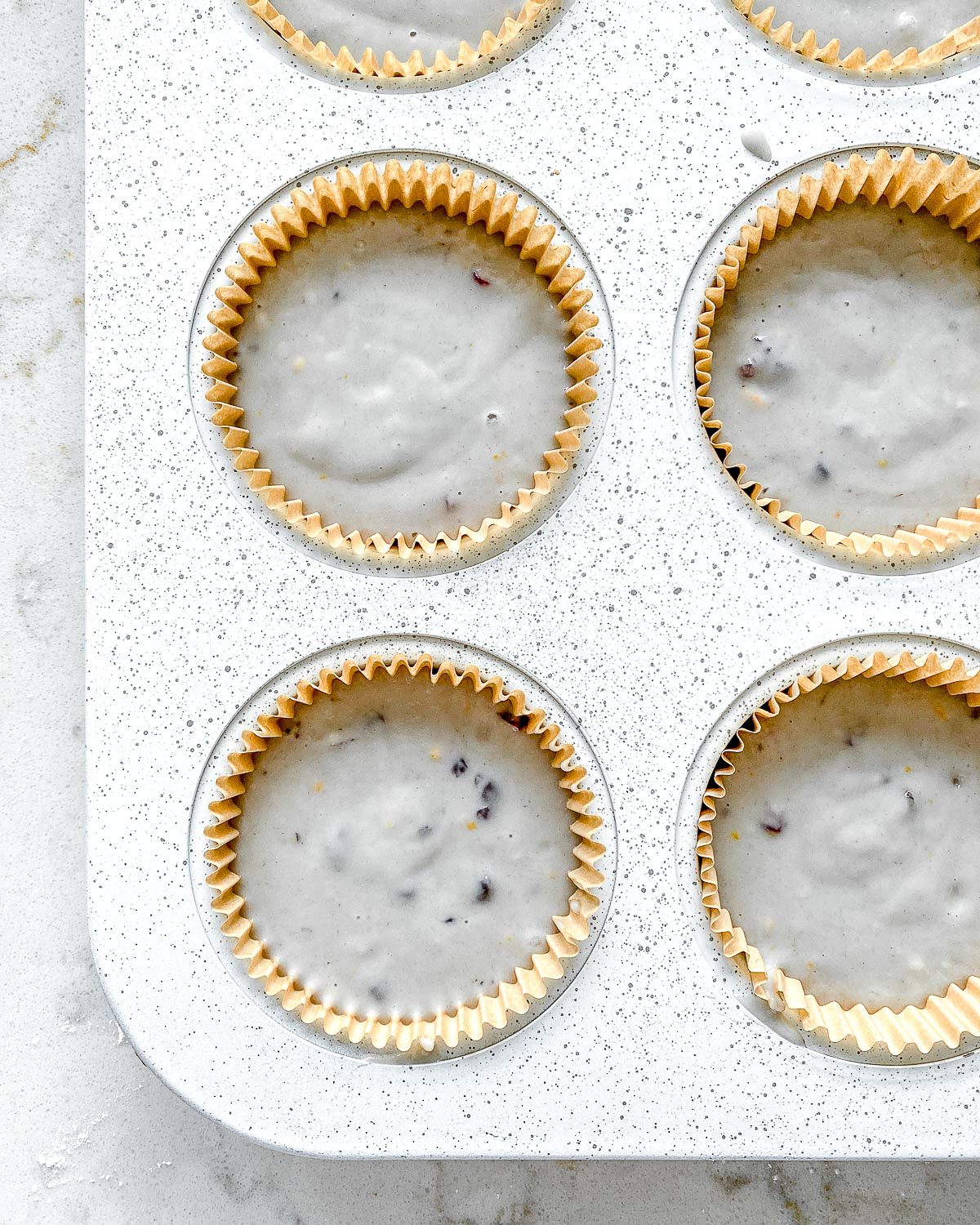 unbaked blackberry orange cupcakes in muffin tin prior to being baked