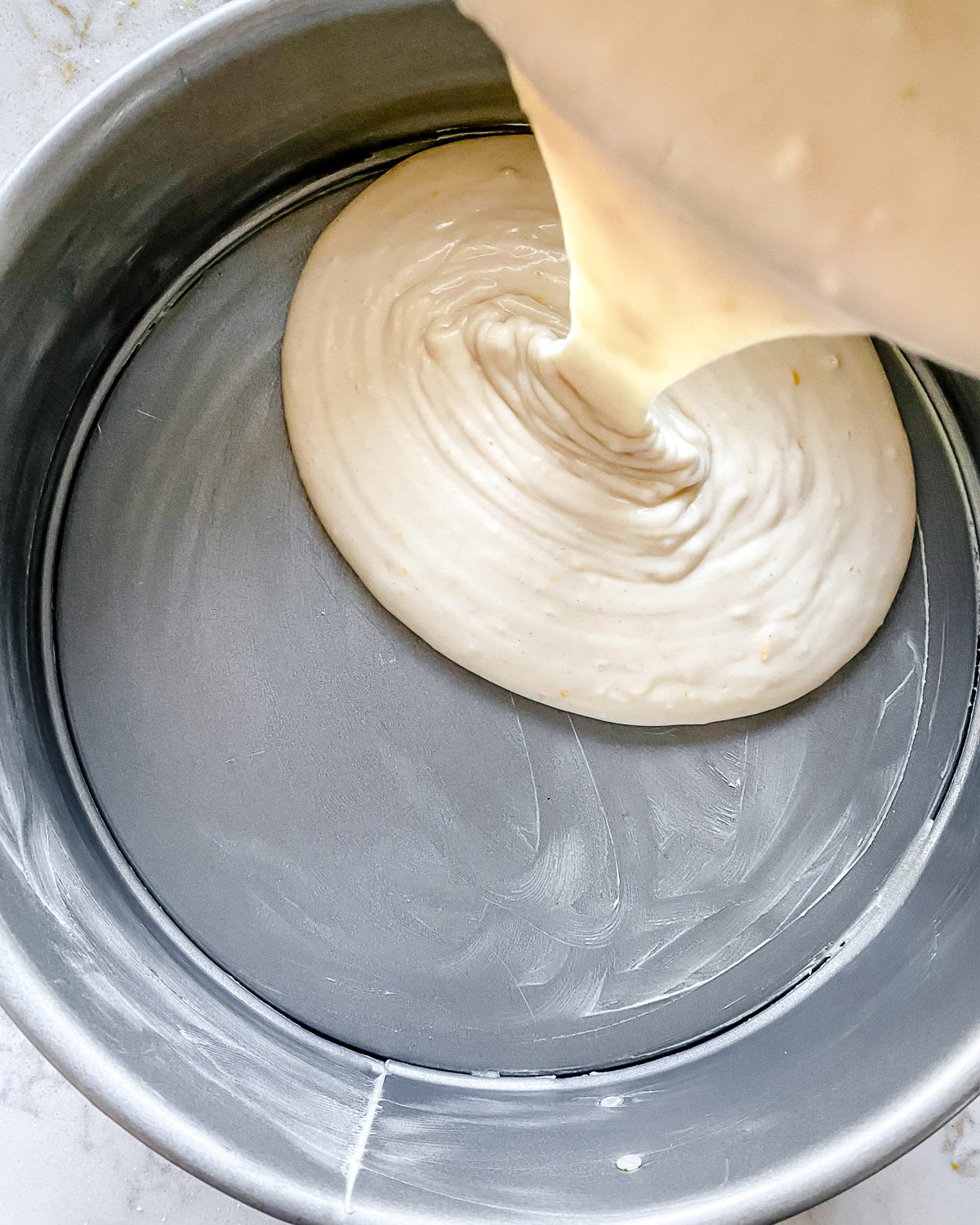process of pouring Lemon Frosting Cake batter into baking pan