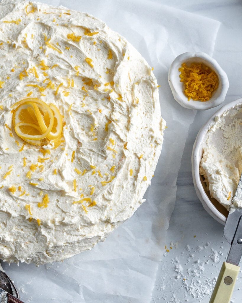 completed lemon cake with ingredients in individual bowls against a white background