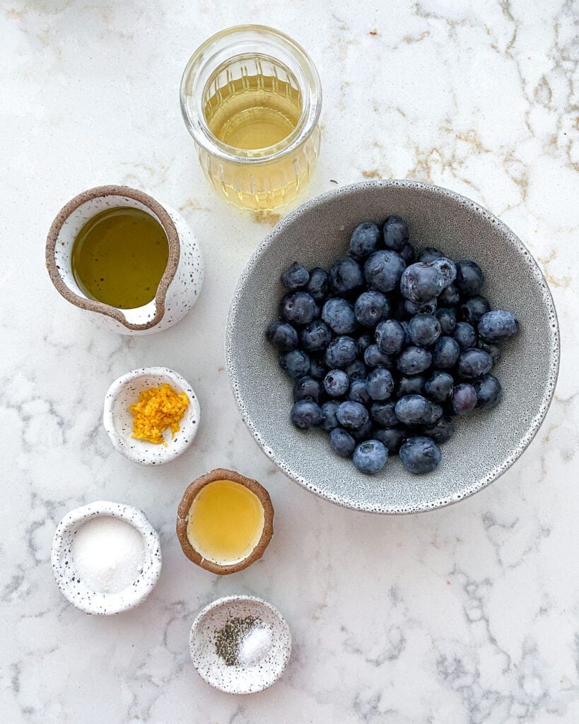 ingredients for blueberry vinaigrette measured out against a white marble surface