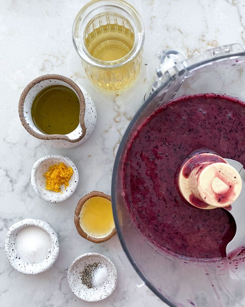 ingredients for blueberry vinaigrette measured out against a white marble surface