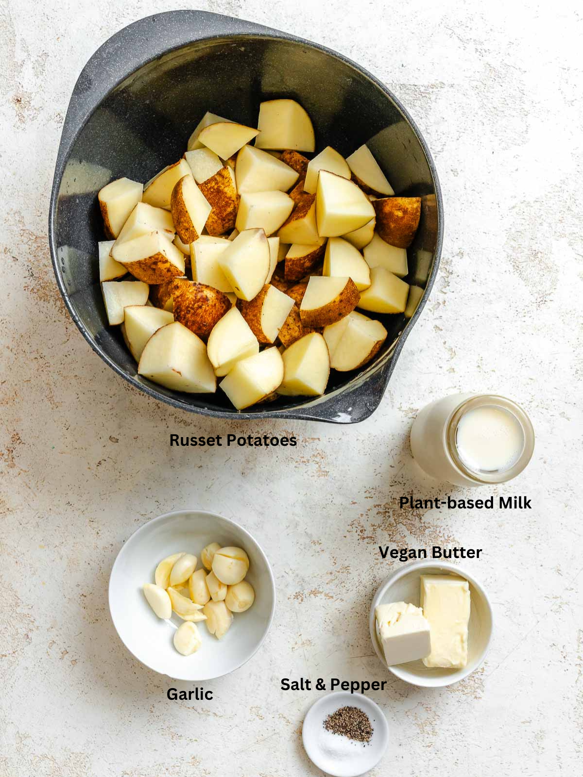 Ingredients for Instant Pot Garlic Mashed Potatoes measured out on a white surface. 
