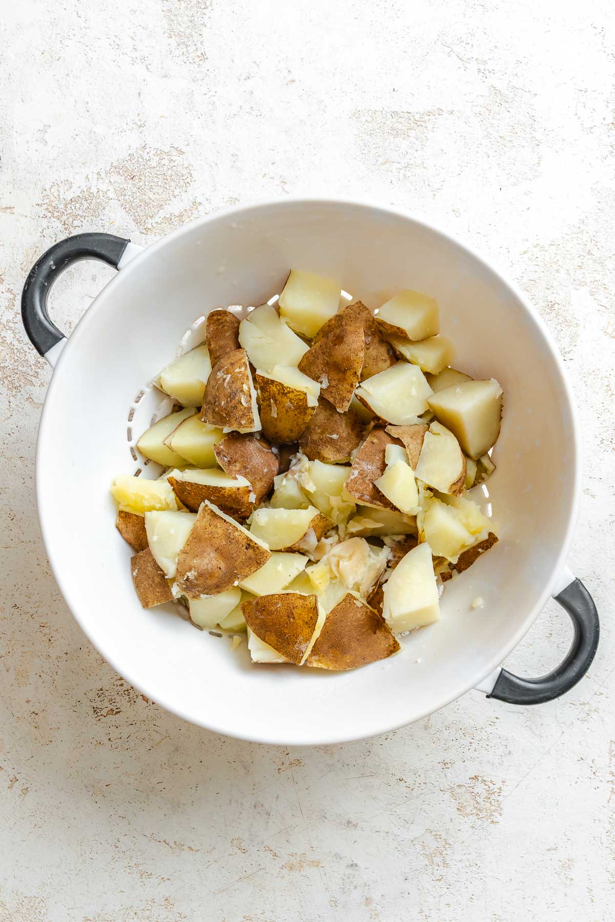 Process shot showing potatoes in a strainer.