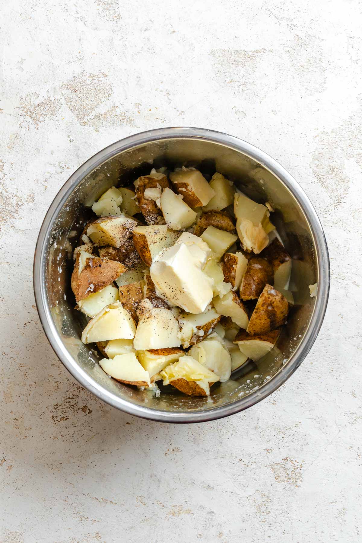 Plant-based milk, vegan butter, salt, and pepper added to the drained potatoes and garlic in the Instant Pot.