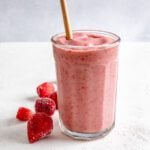 completed Strawberry Yogurt Smoothie in a glass cup with strawberries against a white background
