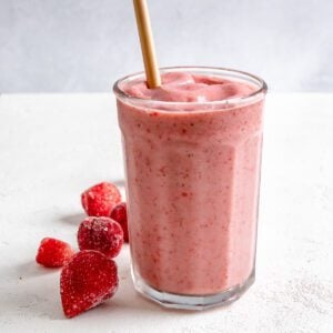 completed Strawberry Yogurt Smoothie in a glass cup with strawberries against a white background