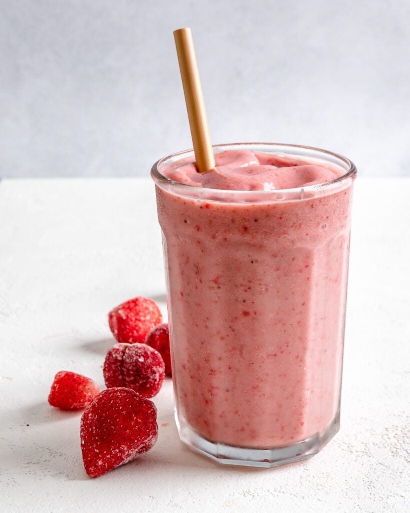 completed Strawberry Yogurt Smoothie in a glass cup with strawberries against a white background
