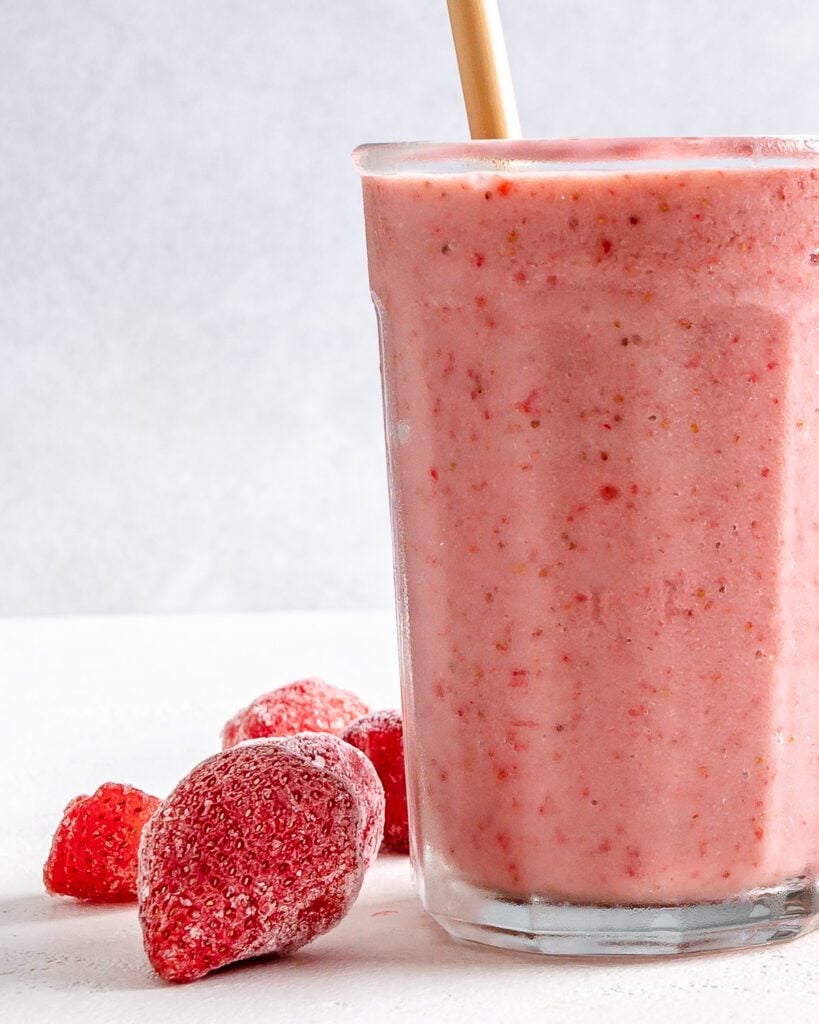 completed Strawberry Yogurt Smoothie in a glass cup with strawberries against a white background