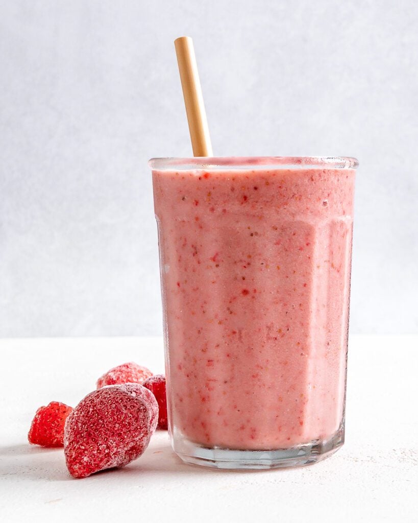completed Strawberry Yogurt Smoothie in a glass cup with strawberries against a white background
