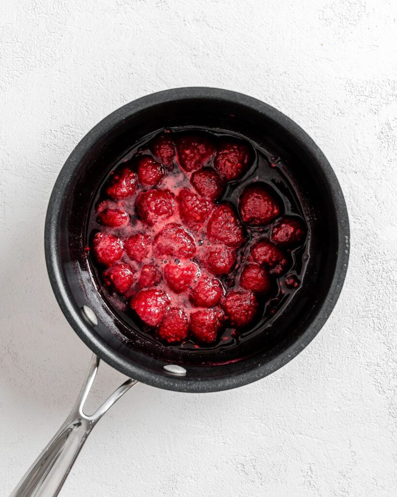 process of cooking raspberries on a black pan against a white background