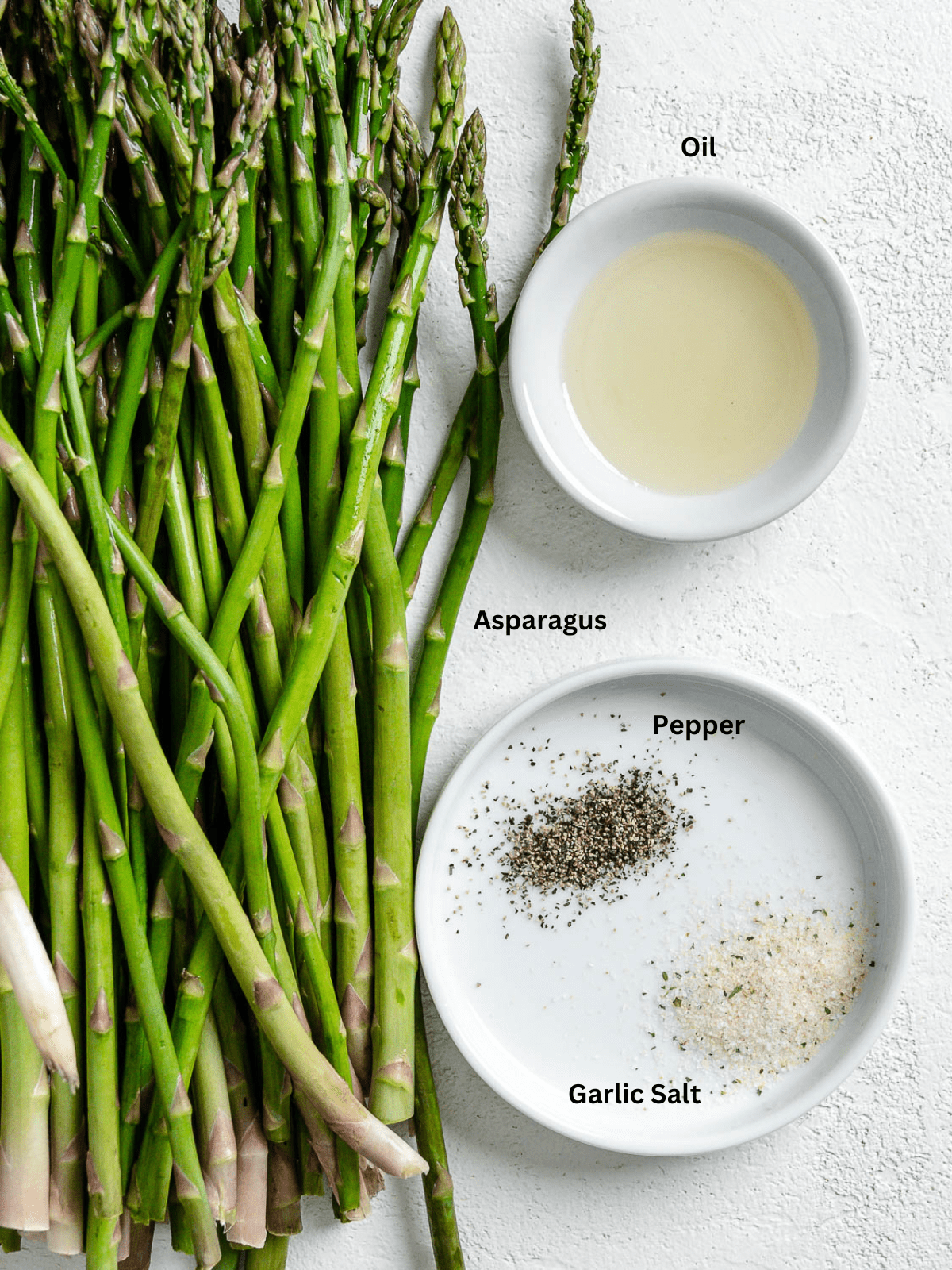 Ingredients for Air Fryer Asparagus measured out on a white surface.