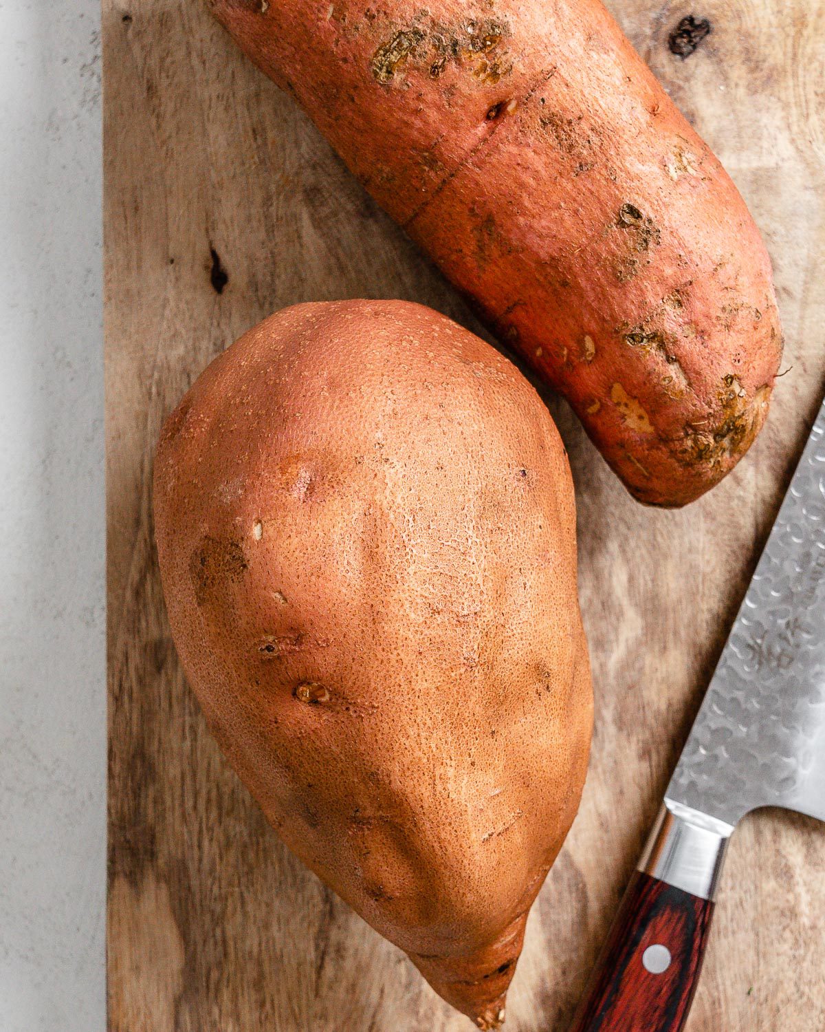 two whole sweet potato wedges with a cutting knife in the background