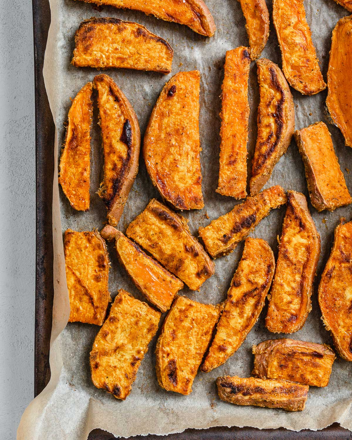 completed sweet potato wedges on a baking tray against a white background