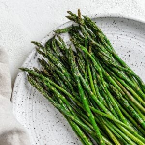 completed air fryer asparagus on a white speckled plate