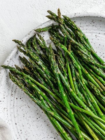 completed air fryer asparagus on a white speckled plate