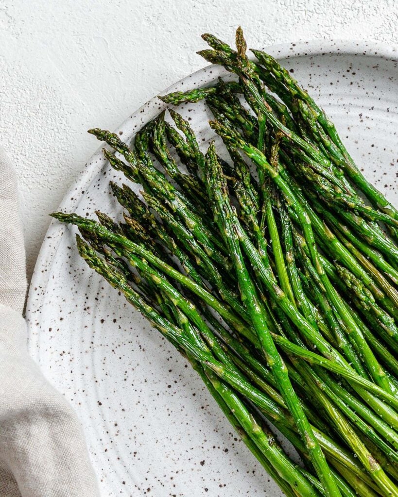 completed air fryer asparagus on a white speckled plate