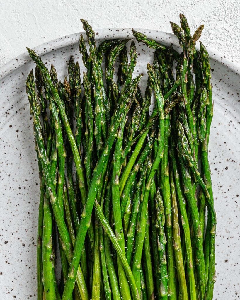 completed air fryer asparagus on a white speckled plate