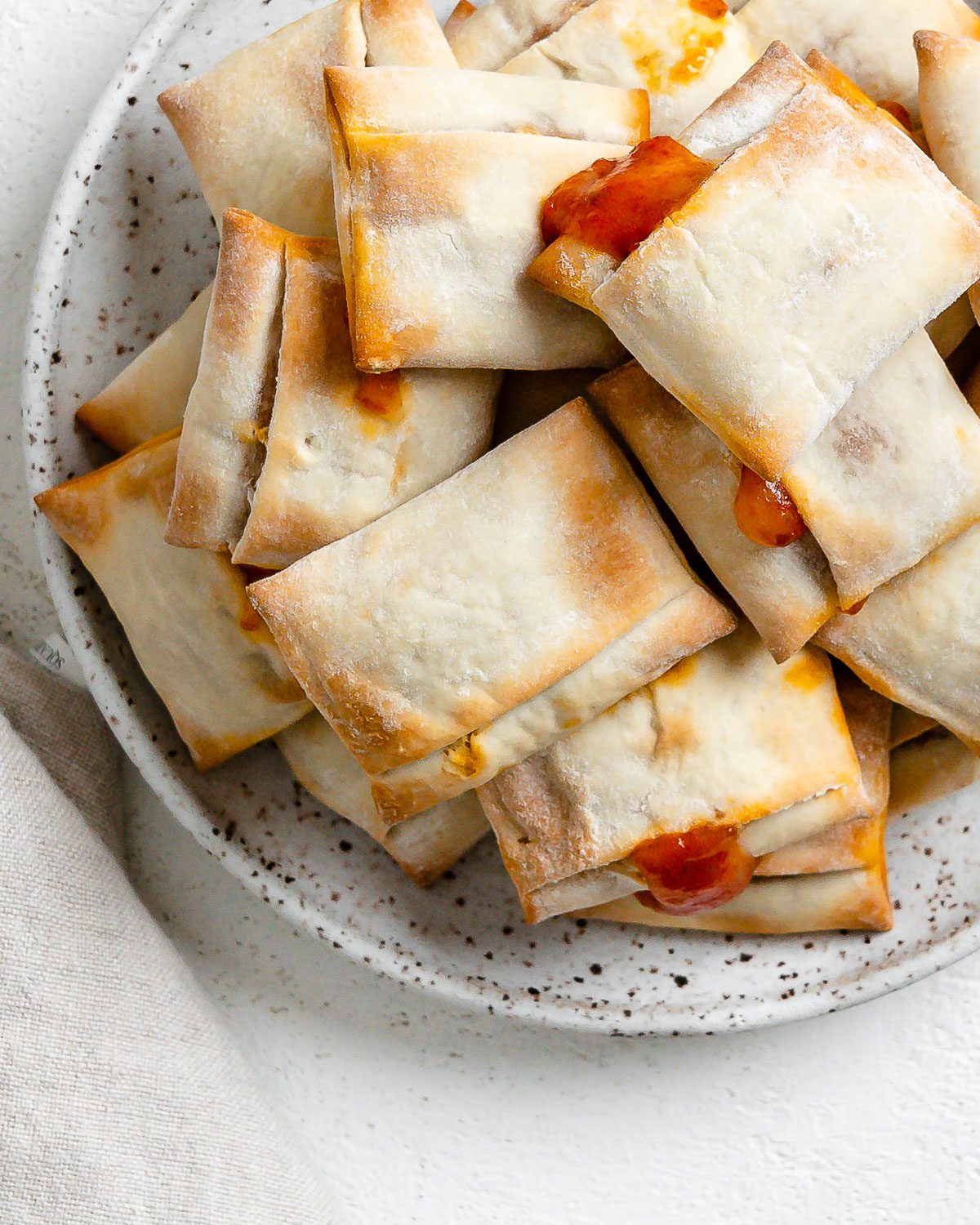 completed Air Fryer Pizza Rolls in a white speckled plate against a white background