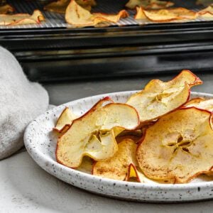 completed Dehydrator Apple Chips on a white plate with chips in the background