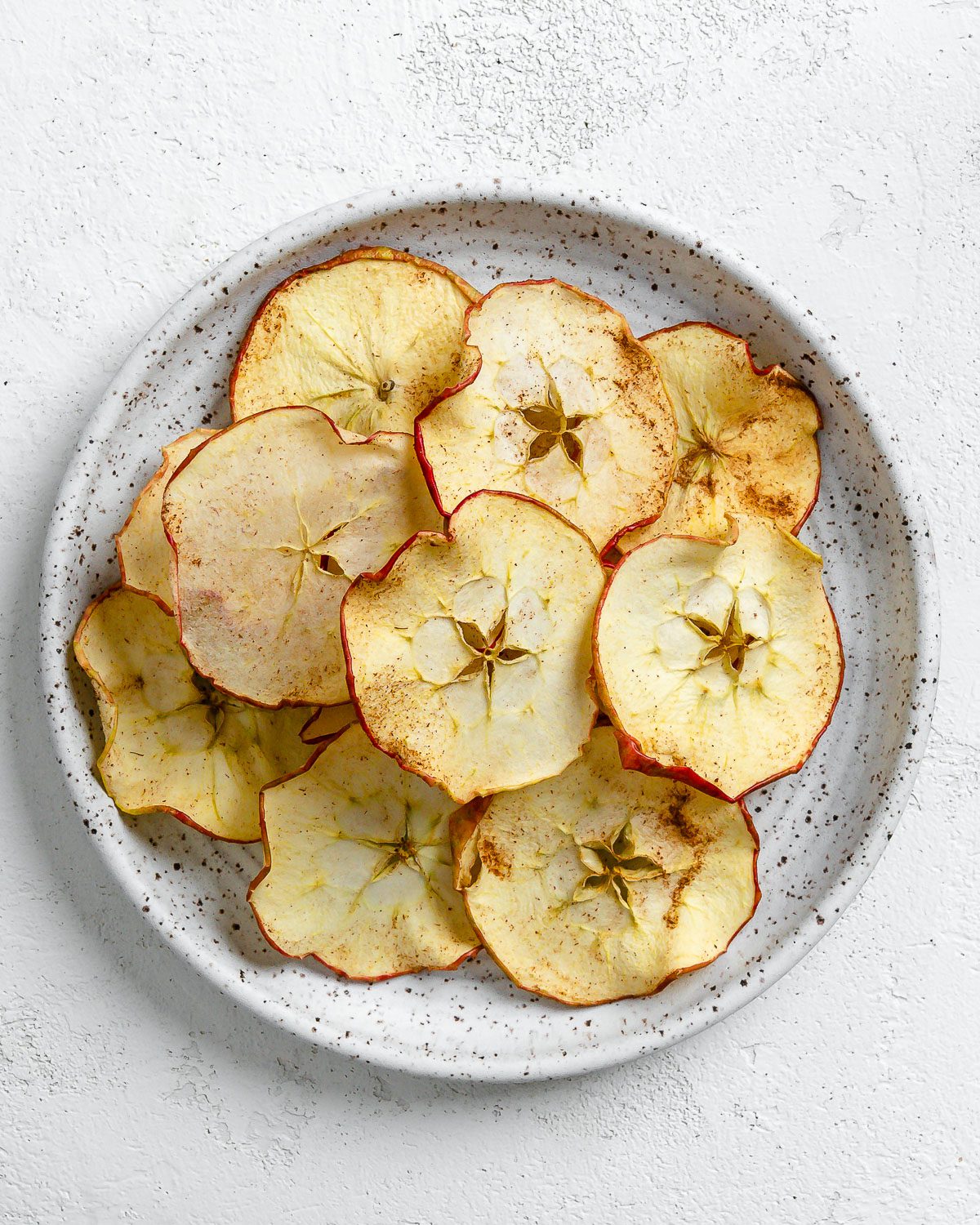 completed Dehydrator Apple Chips on a white plate against a white background