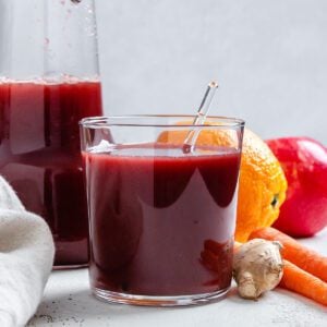 completed Immunity Boosting Juice in two glasses with ingredients in the background