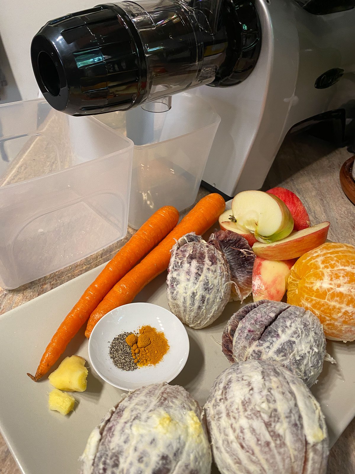 ingredients for Immunity Boosting Juice spread out on a white surface alongside a juicer