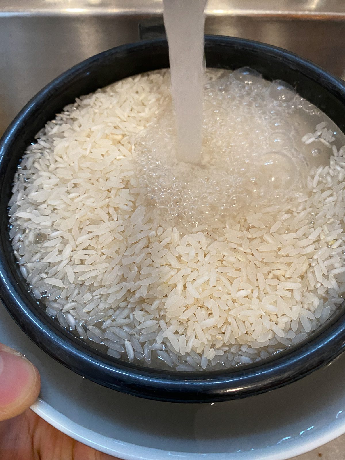 process shot of water being added to rice in strainer