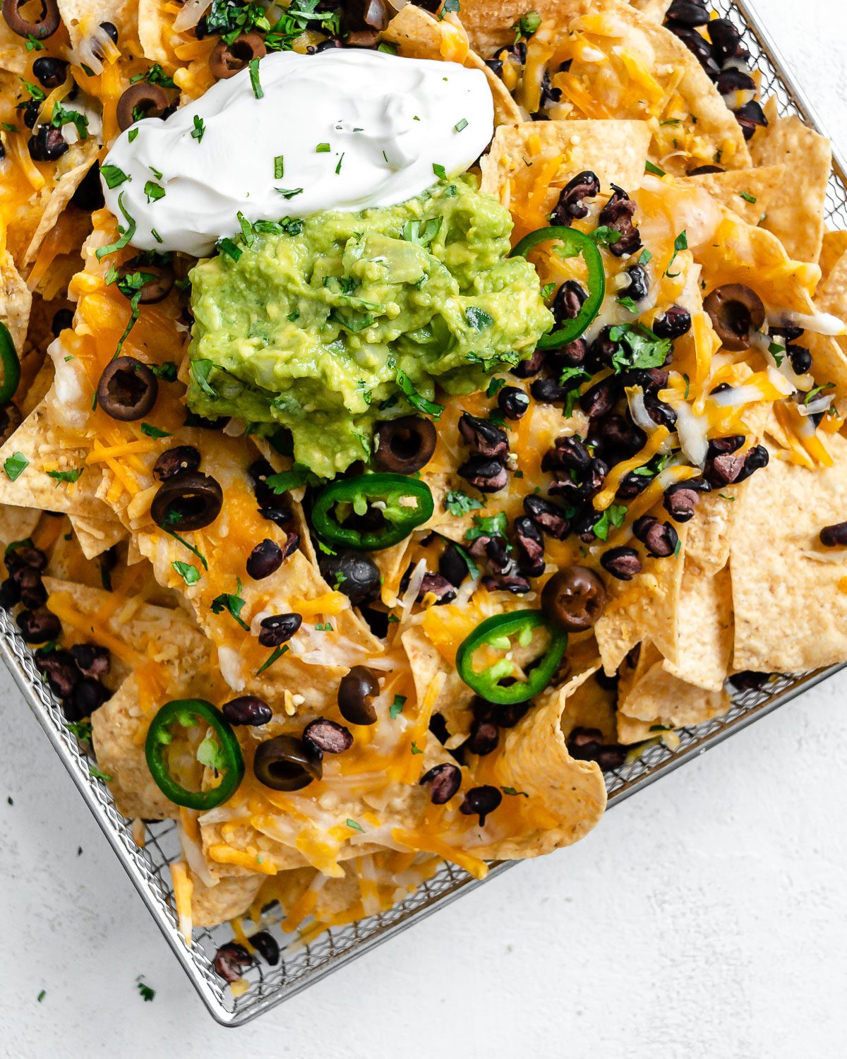 completed Vegan Air Fryer Nachos on air fryer tray against white surface