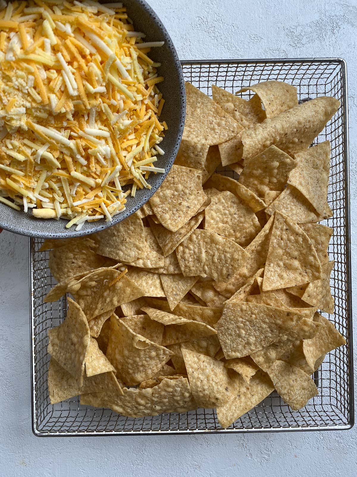 process shot of vegan cheese being added to chips on air fryer rack