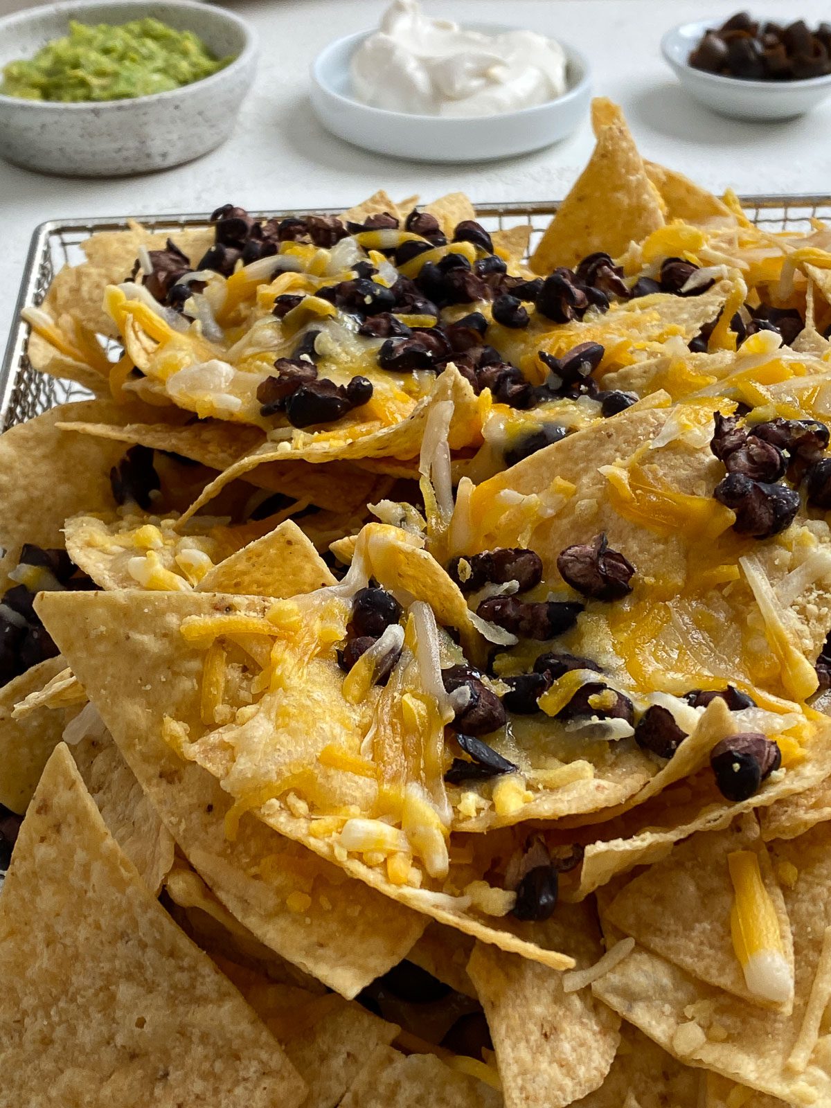 Vegan Air Fryer Nachos on air fryer tray against white surface prior to being air-fried