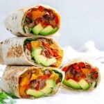 four completed Butternut Squash Burritos stacked on one another against a light background