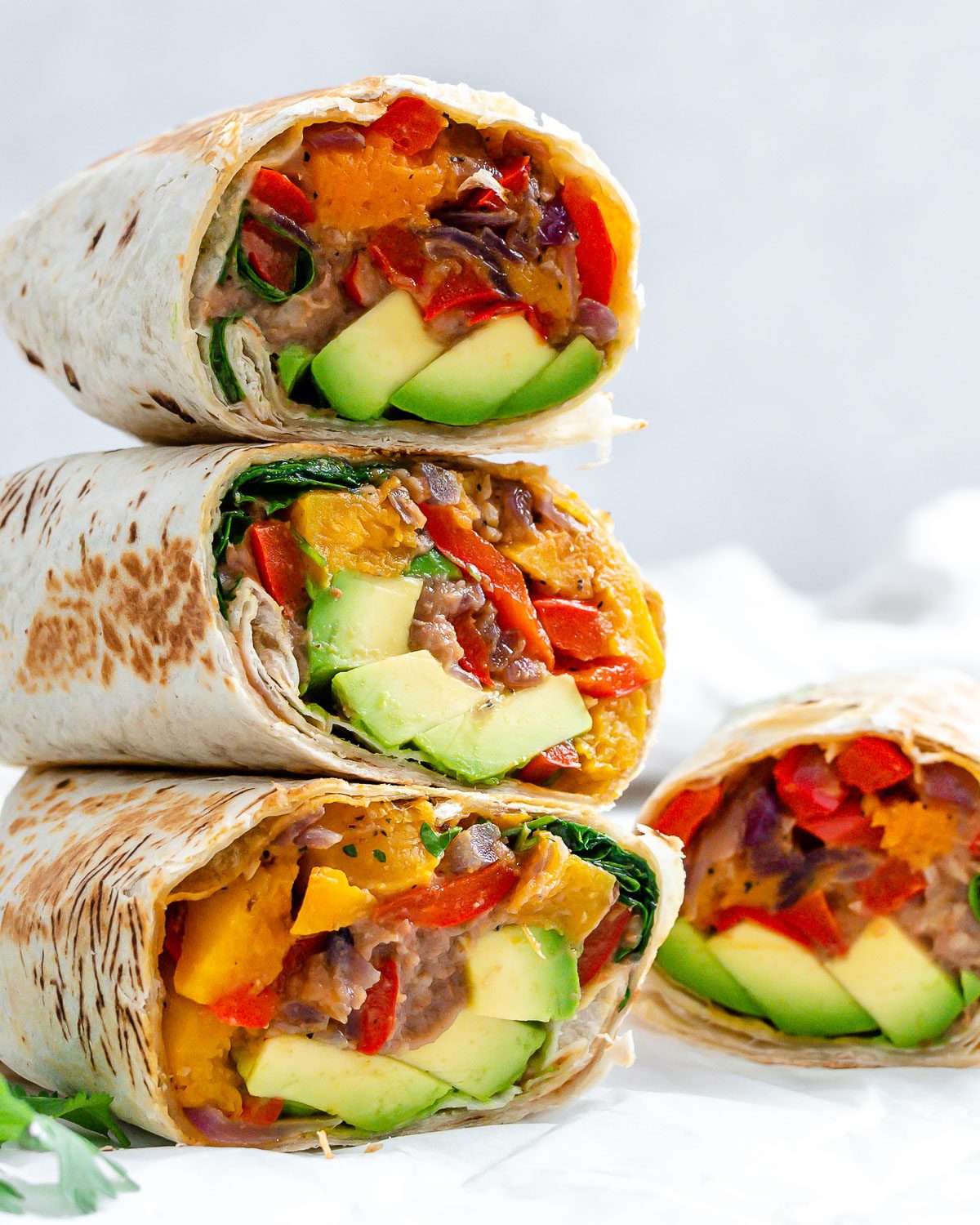 four completed Butternut Squash Burritos stacked on one another against a light background