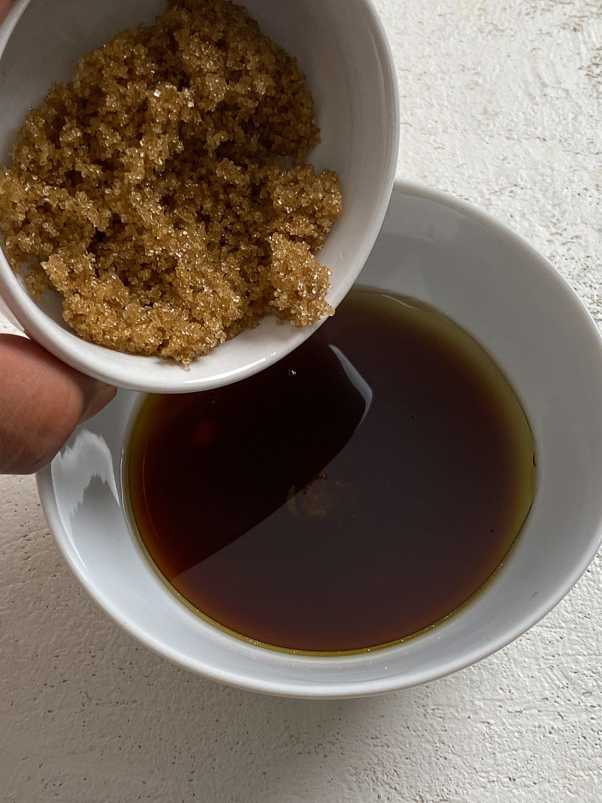 process of brown sugar added to bowl of sauce