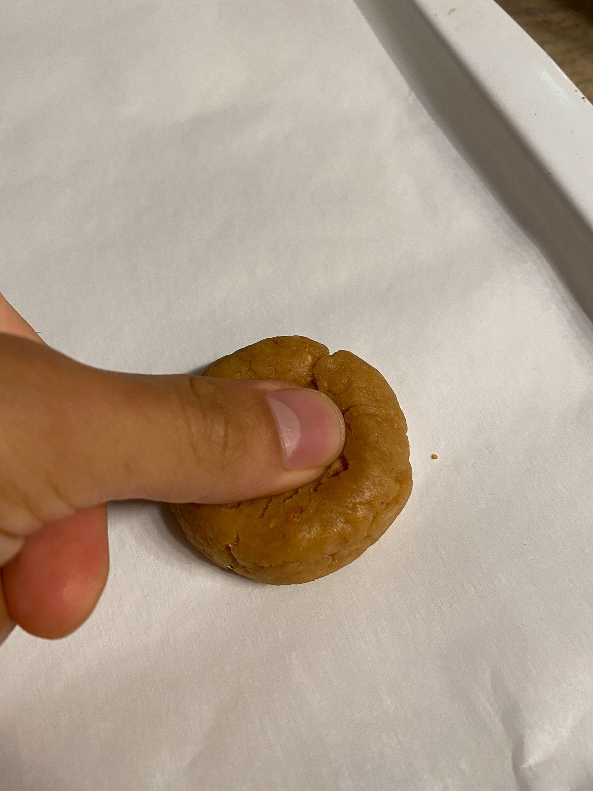 process of creating thumbprint indent into dough on a baking sheet
