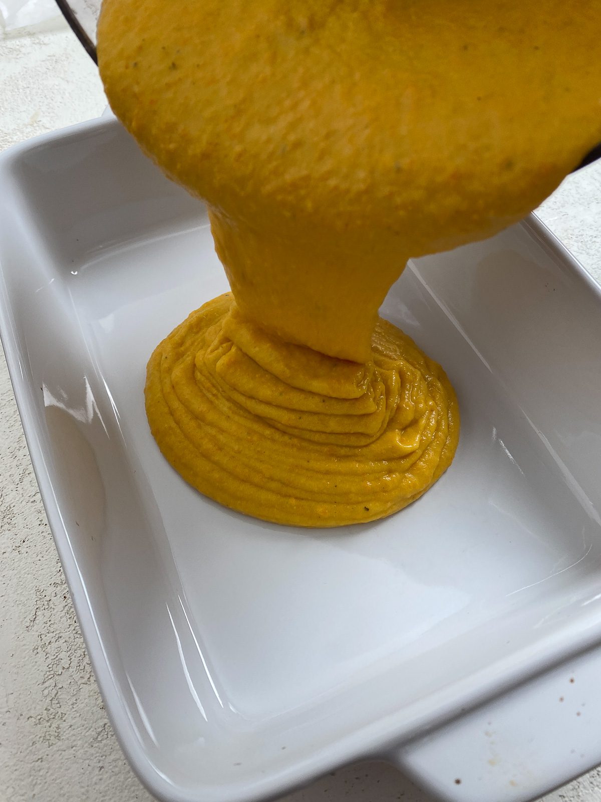 process shot showing vegan cheese being poured into baking dish