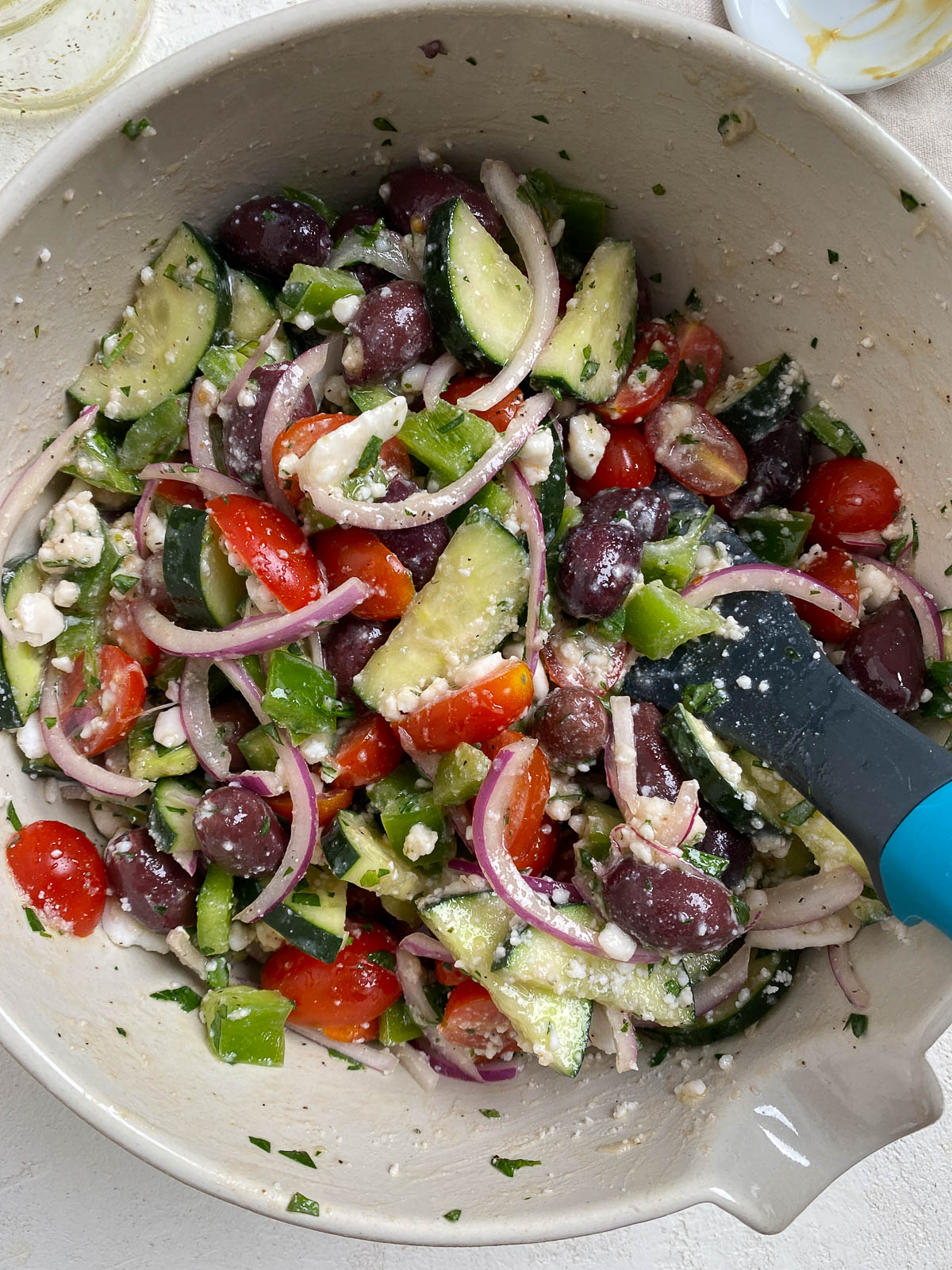 process shot of mixing vegan greek salad ingredients together