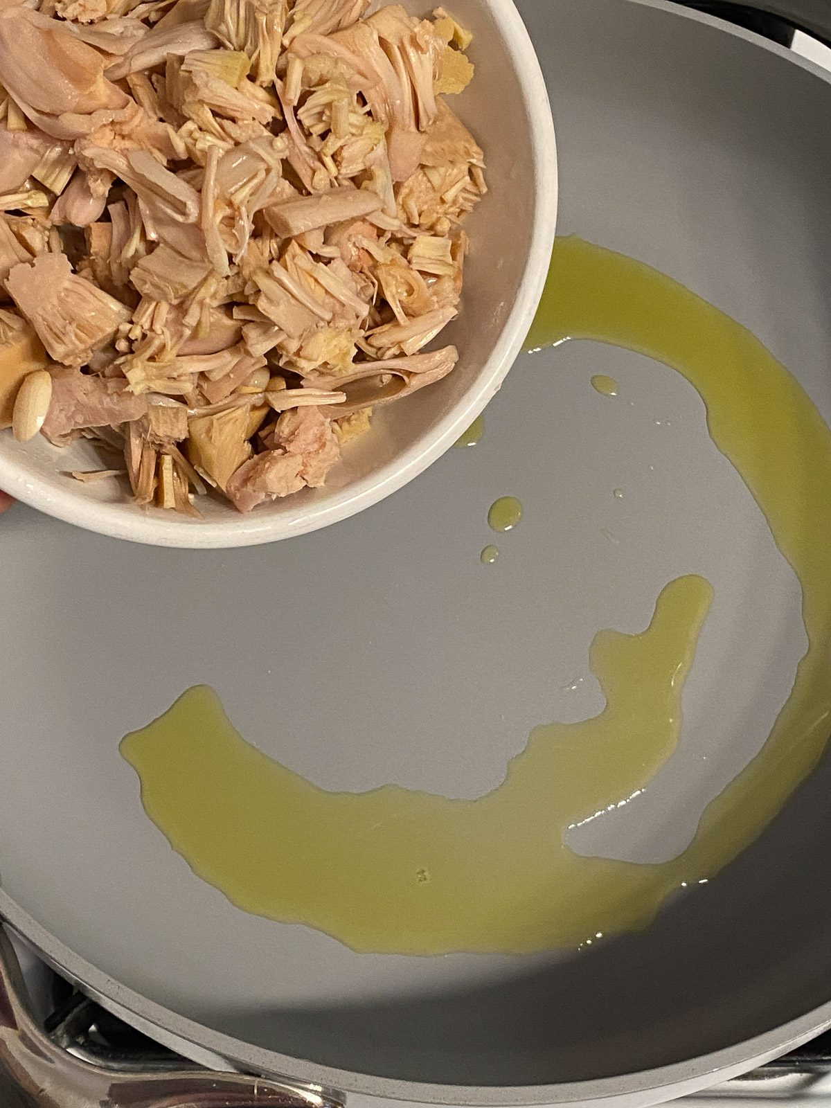 process shot showing jackfruit being added to pan of oil