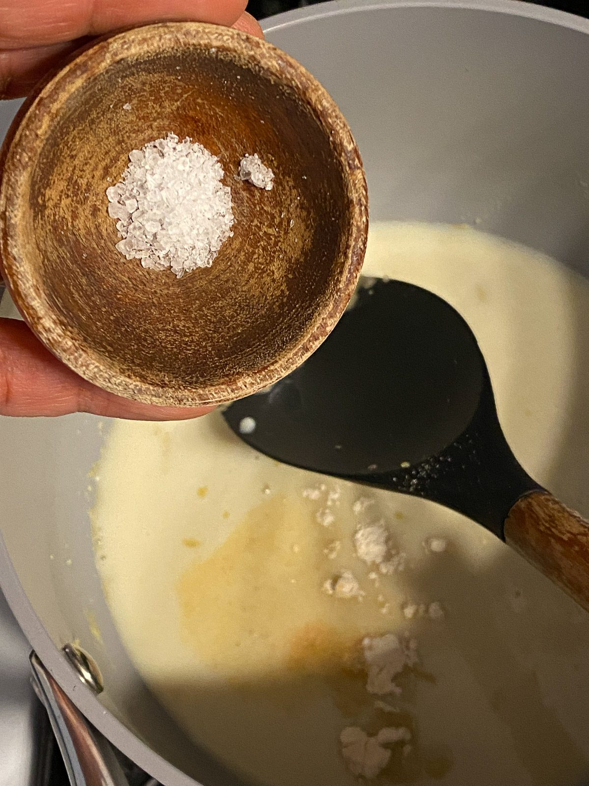 process shot showing salt added to cheese sauce