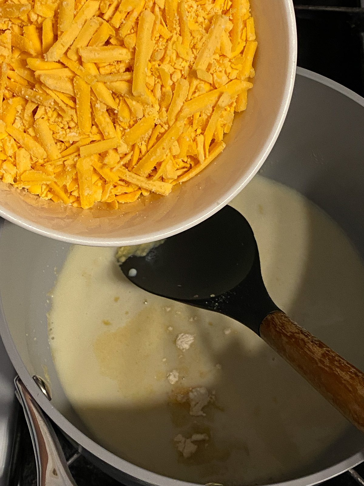 shredded vegan cheese being poured into cheese mixture