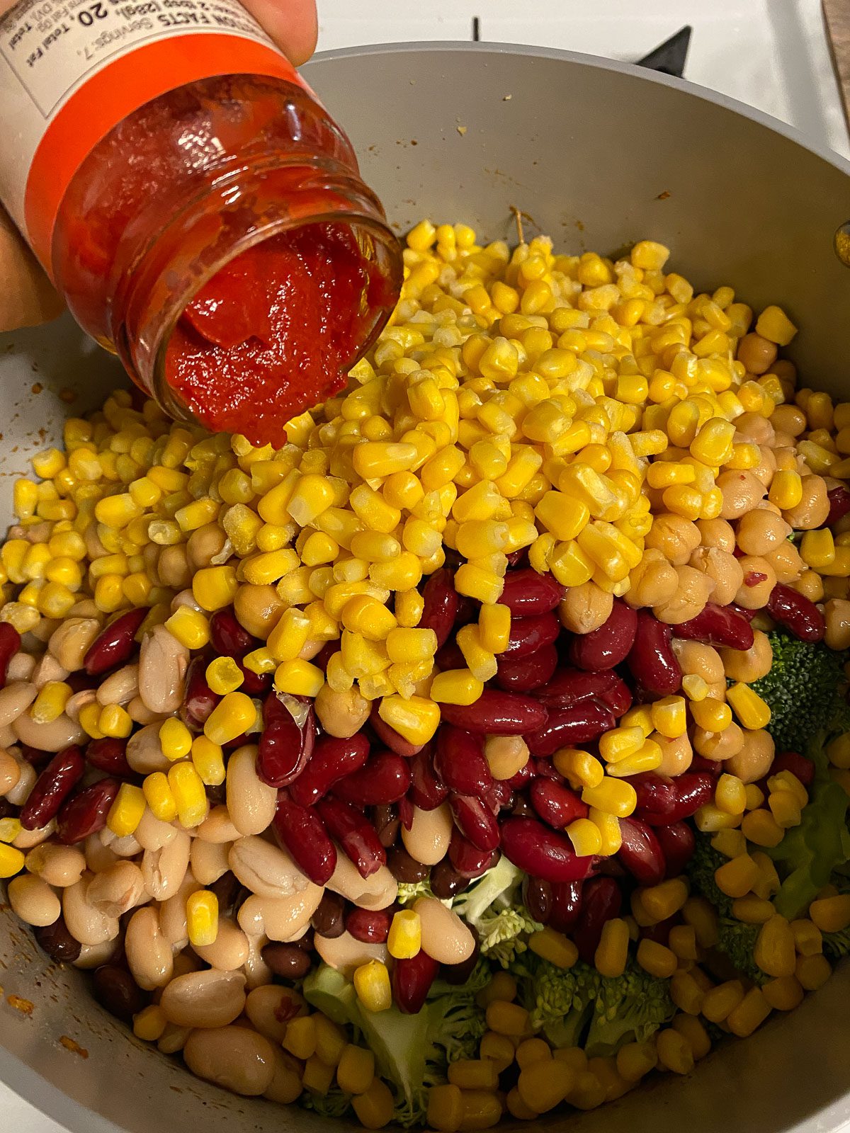 process of adding tomato paste into mixed pan of veggies