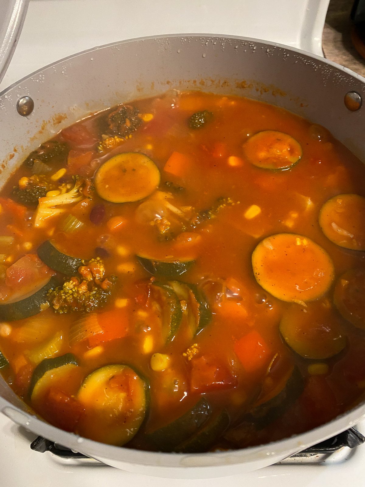 process of adding veggie broth to mixed pan of veggies