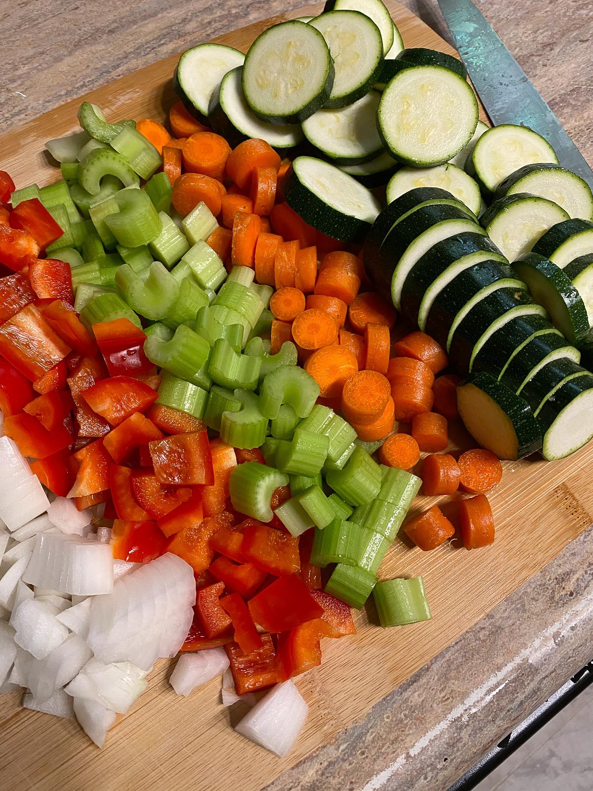 chopped and cut ingredients for vegetable stew against cutting board