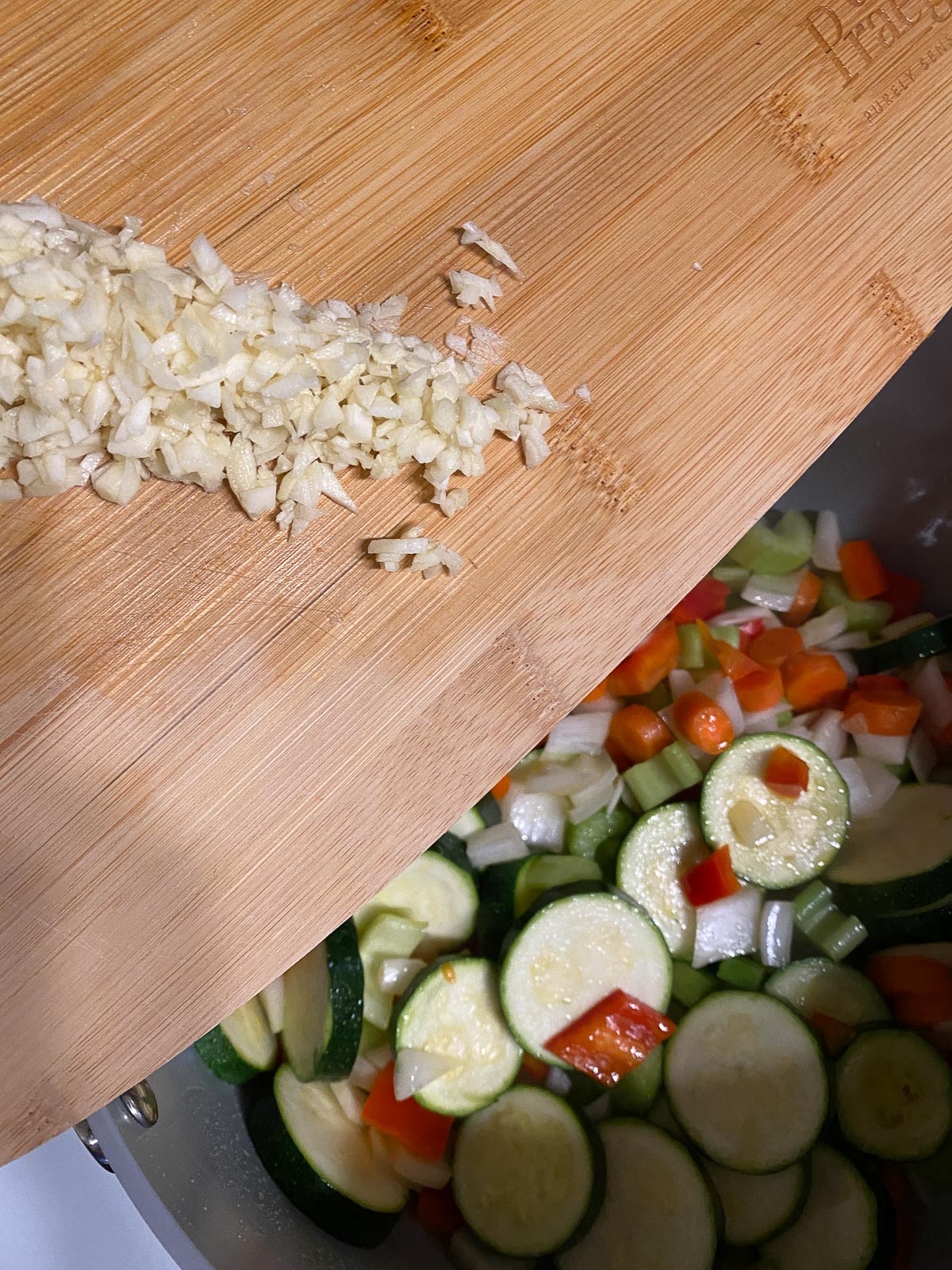 process of adding minced garlic into pan of veggies