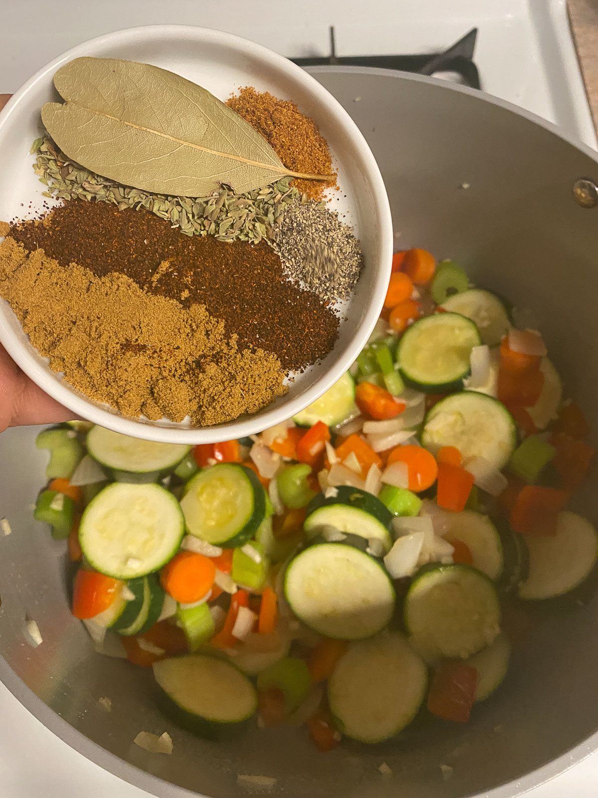 process of adding spices to mixed pan of veggies